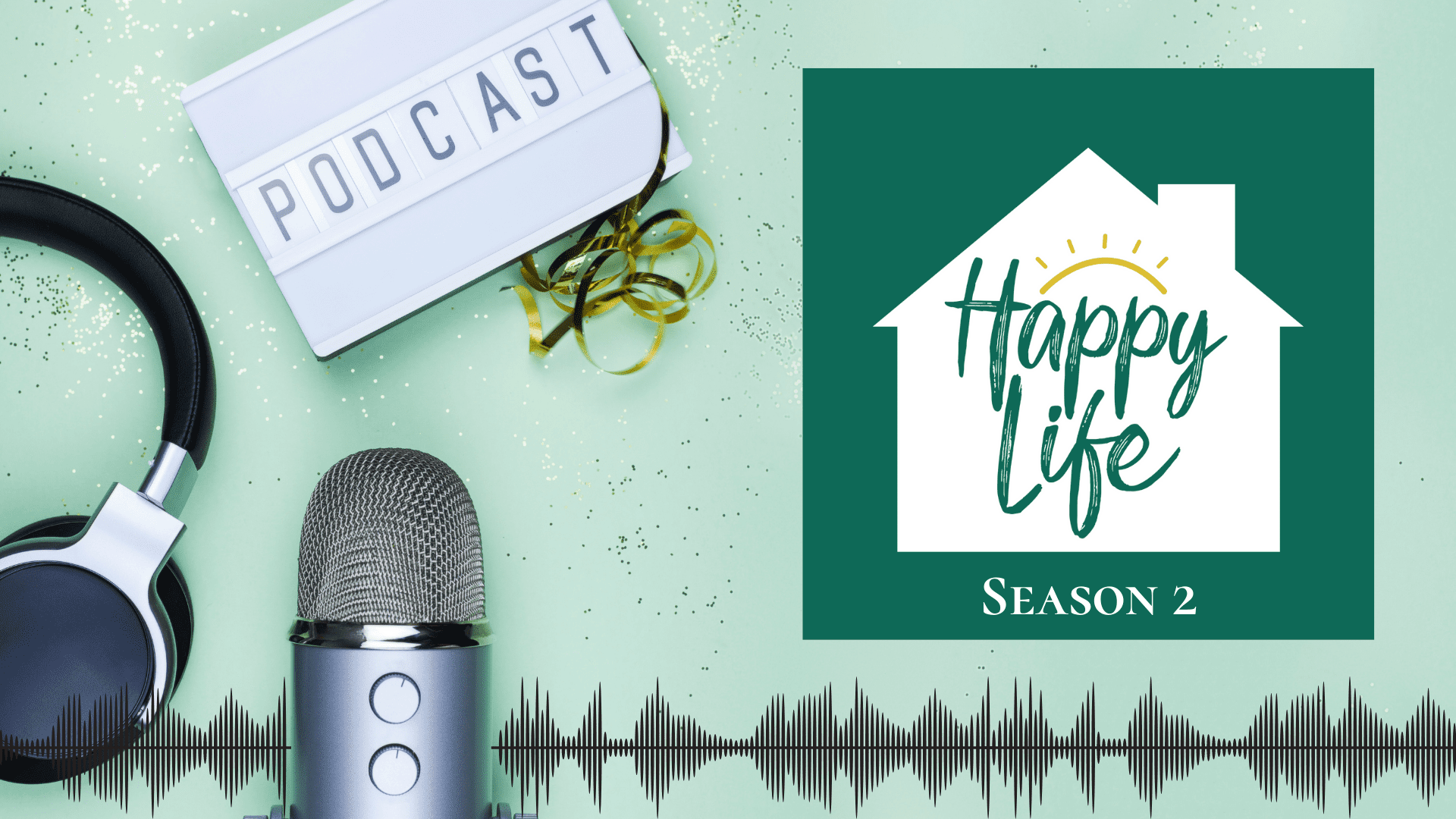 A microphone, headphones and a sign that says podcast are laid out on a table with the graphic of the Happy Life podcast logo.