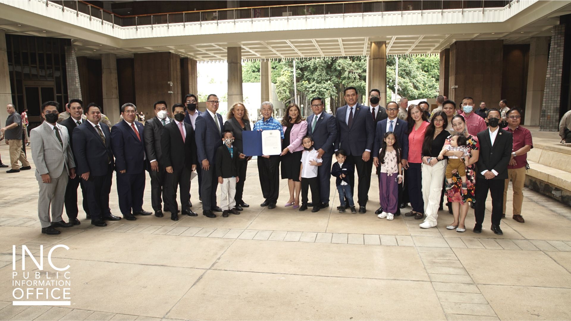 Hawaii State Governor David Ige and Senators Senator Lynn DeCoite and Bennette Misalucha (in pink) hold the certificate presented to the INC on July 8, 2022. They are flanked by INC ministers and their families.